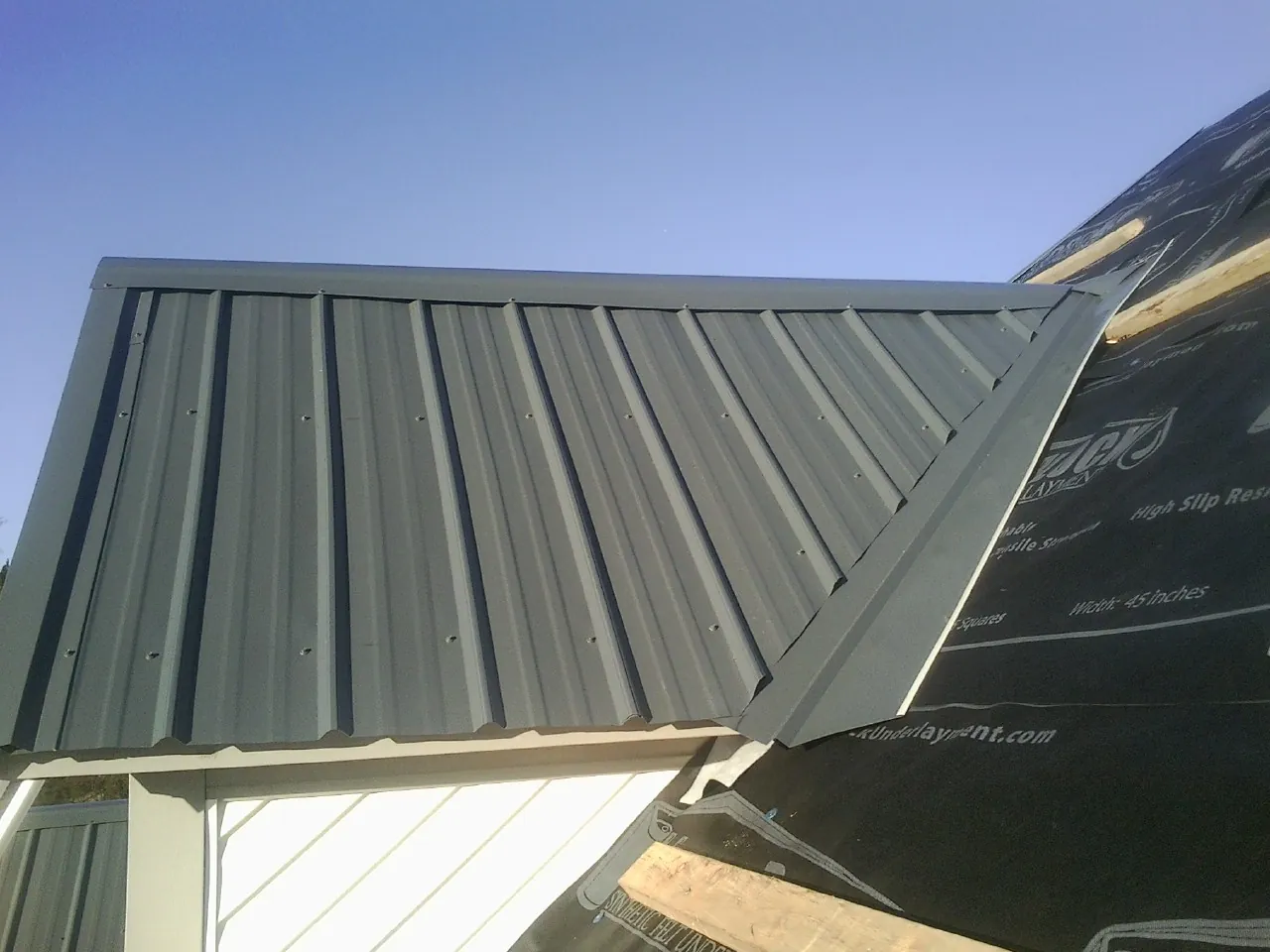 Gray metal roof panels going on over a garage gable in Rising Sun
