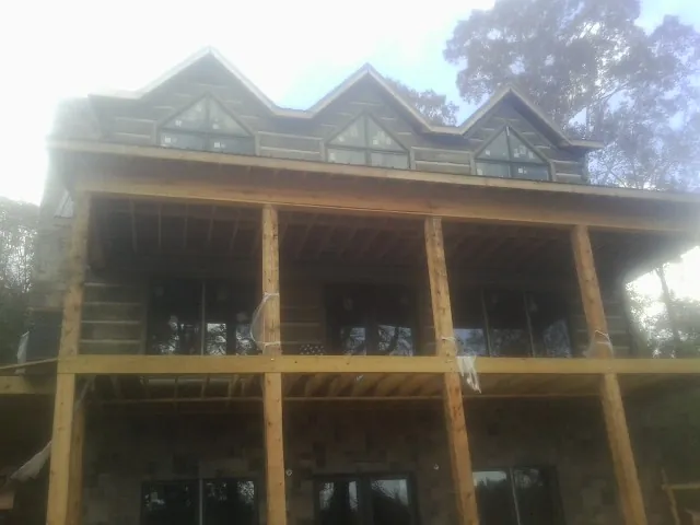 Dormers and porch framing on a large log home under construction — Roof Coating work by our crew in Rising Sun