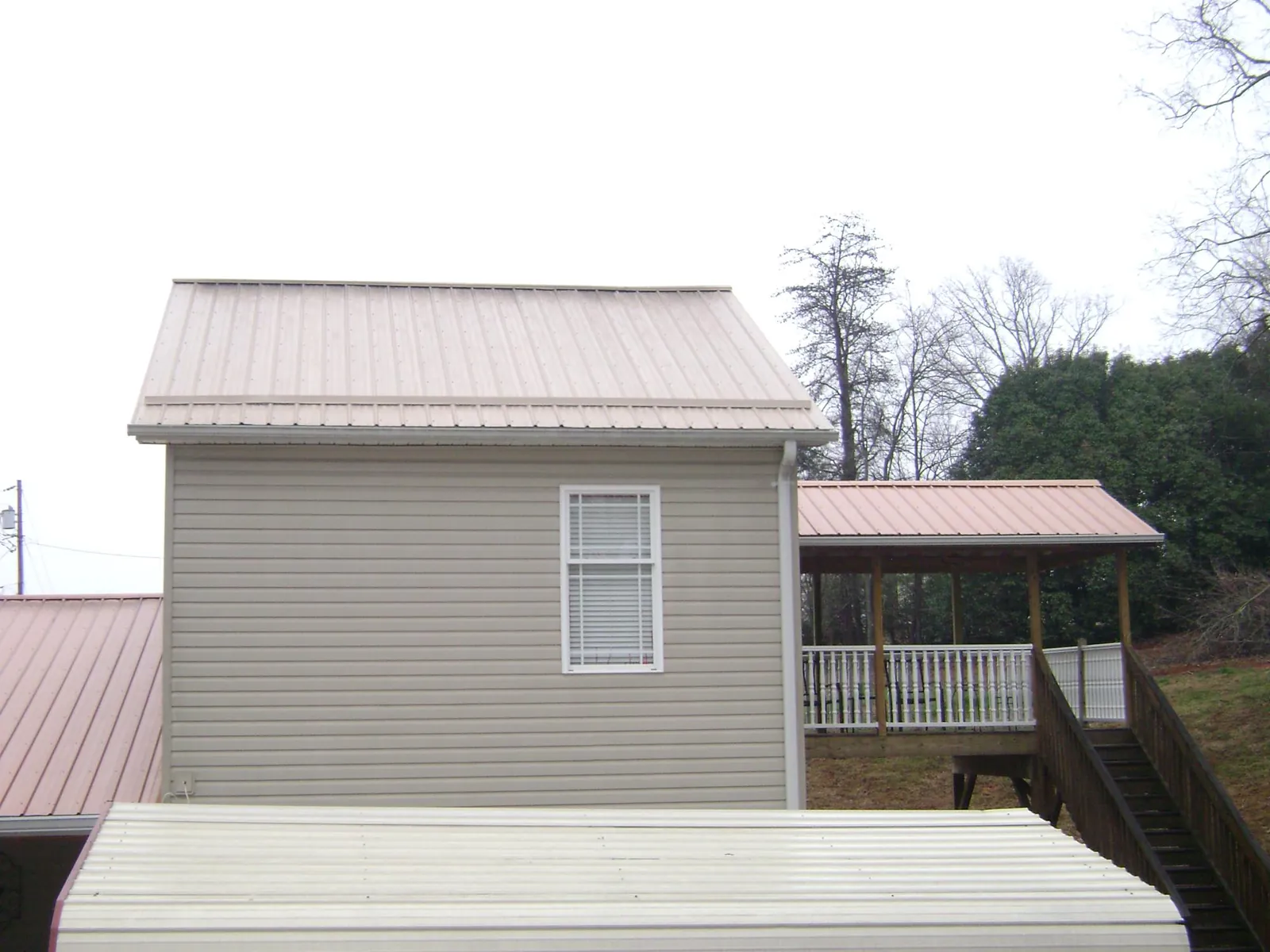 Tan metal roofs on a two story addition and attached porch, from a Roof Replacement job in Rising Sun